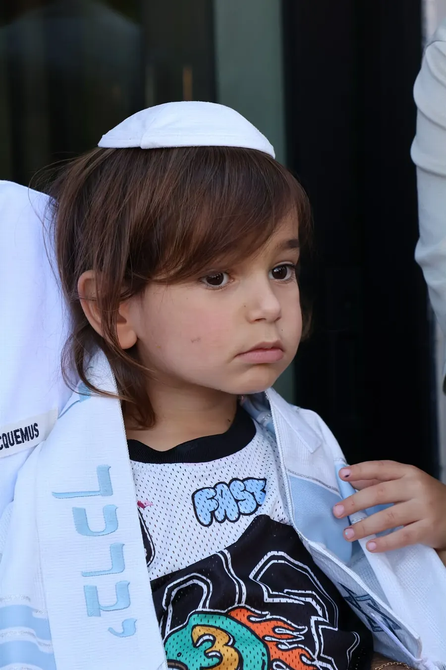 Young child wearing a kippah and tallit at a family event, photographed by Lihi Matzri