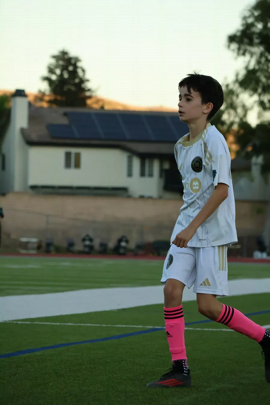 Young player walking across the field in bright pink socks